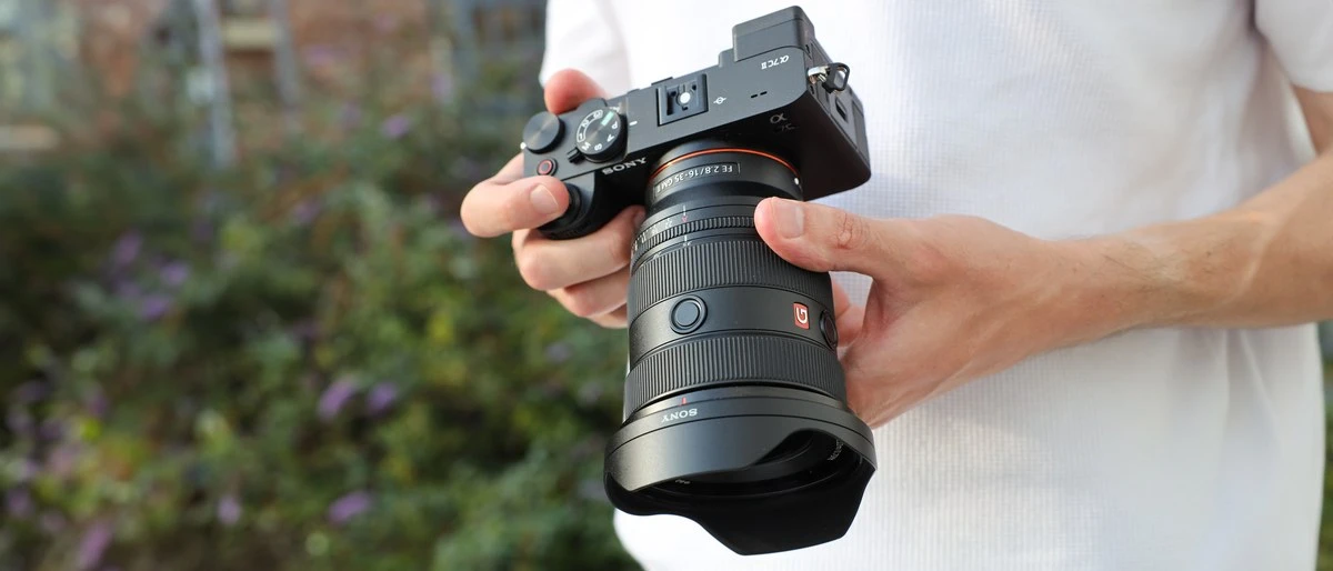 Фотограф тримає компактну повнокадрову камеру Sony a7C II з професійним ширококутним зумом Sony FE 16-35mm f/2.8 GM II та блендою
